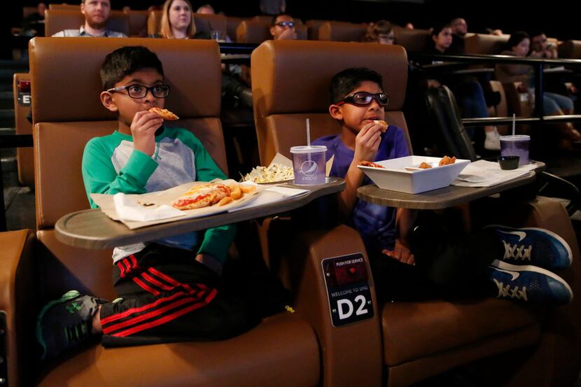 Akash Moparty, 6 and brother Jay Moparty, 9, of Lewisville watch trailers as they eat before...