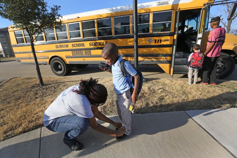 Chanelle Cook ties her son's shoe after he is dropped off at Buckeye Trail Commons by the...