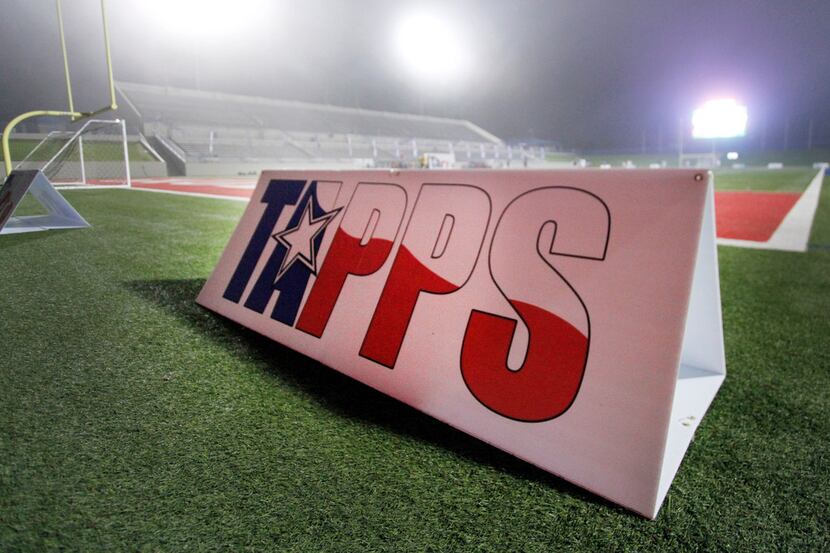 A TAPPS sign is on the field backlit from stadium lights in the fog. Ursuline defeated John...