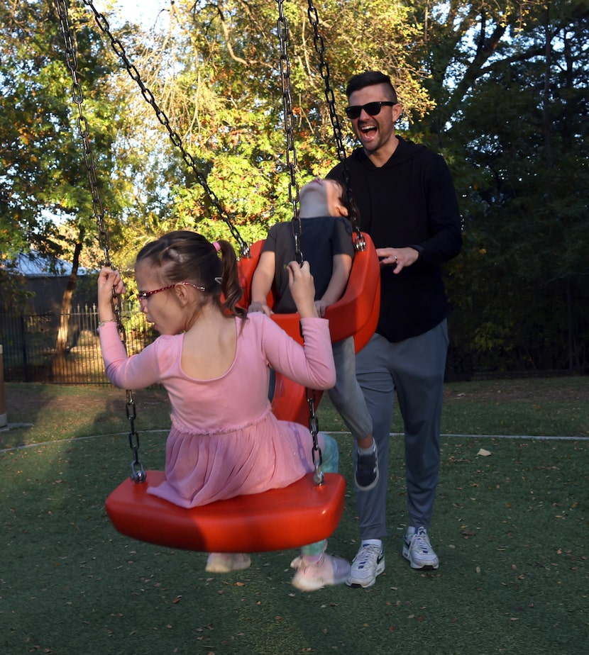 “Even my laugh sounds different,” says Jake Kemp, right, working to push a tandem swing for...