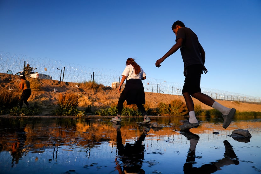 A migrant group steps across stones in the Rio Grande to get to the U.S. side at Gate 42 in...