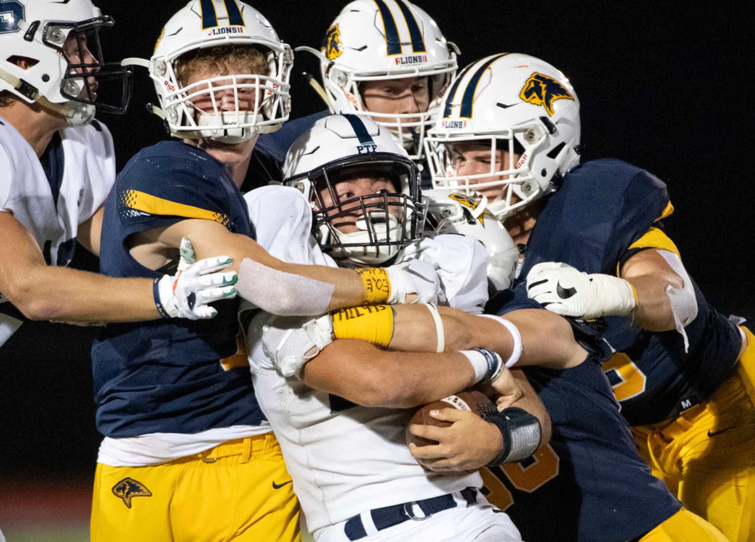 Fort Worth All Saints senior running back Jacob Matlock (22) is wrapped up by Plano...