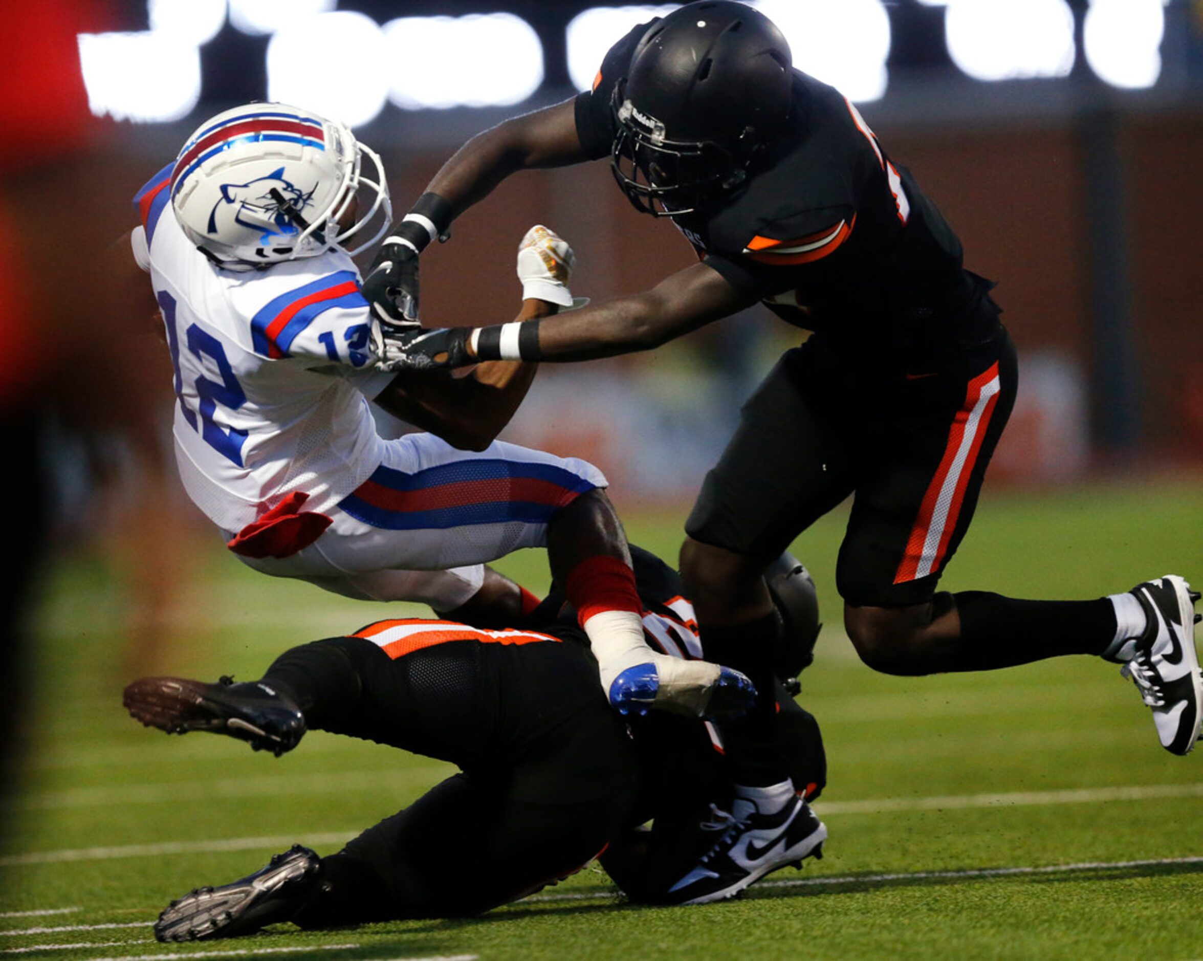 Duncanville running back Suavevion Persley (12) is tackled by Lancaster defensive back Kahn...