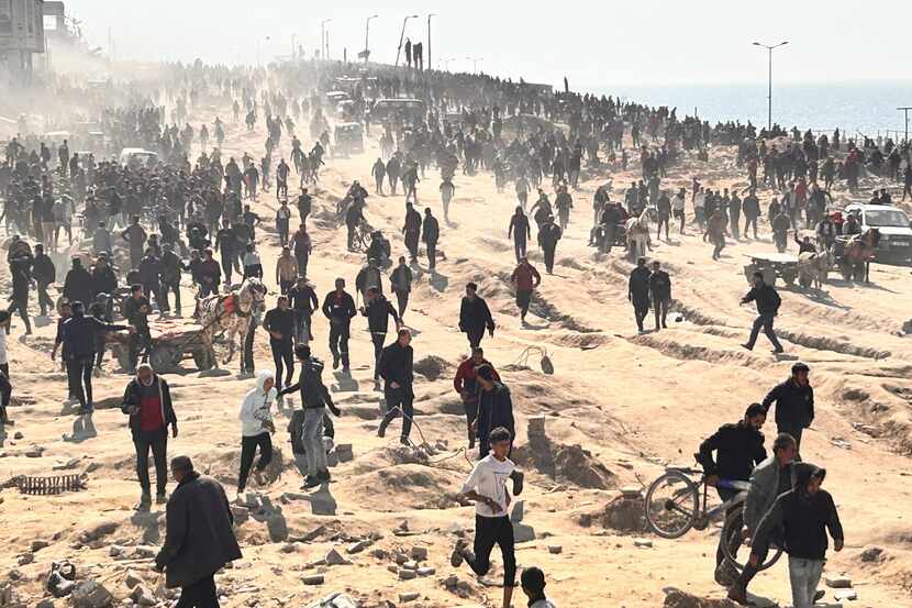 Palestinos esperan a recibir ayuda humanitaria en una playa en Ciudad de Gaza, en la Franja...