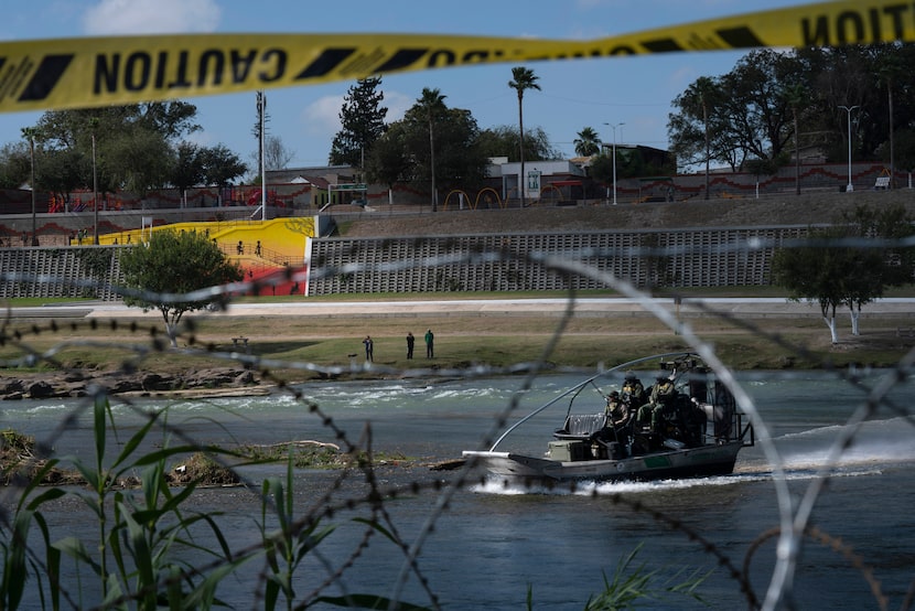 People in Piedras Negras, Mexico, take photos through recently installed concertina wire of...