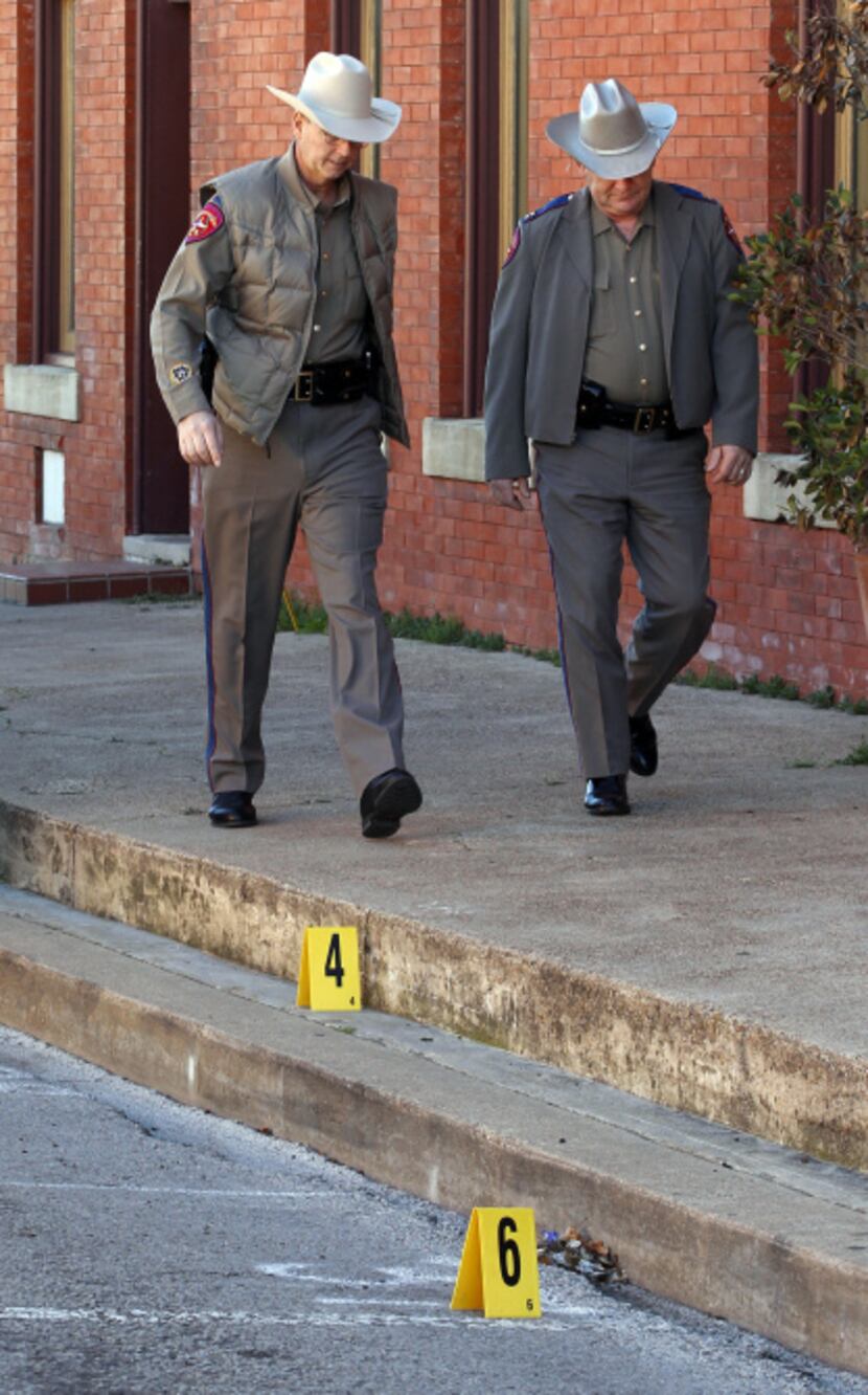 Law enforcement officers walked past some evidence markers that were placed in downtown...