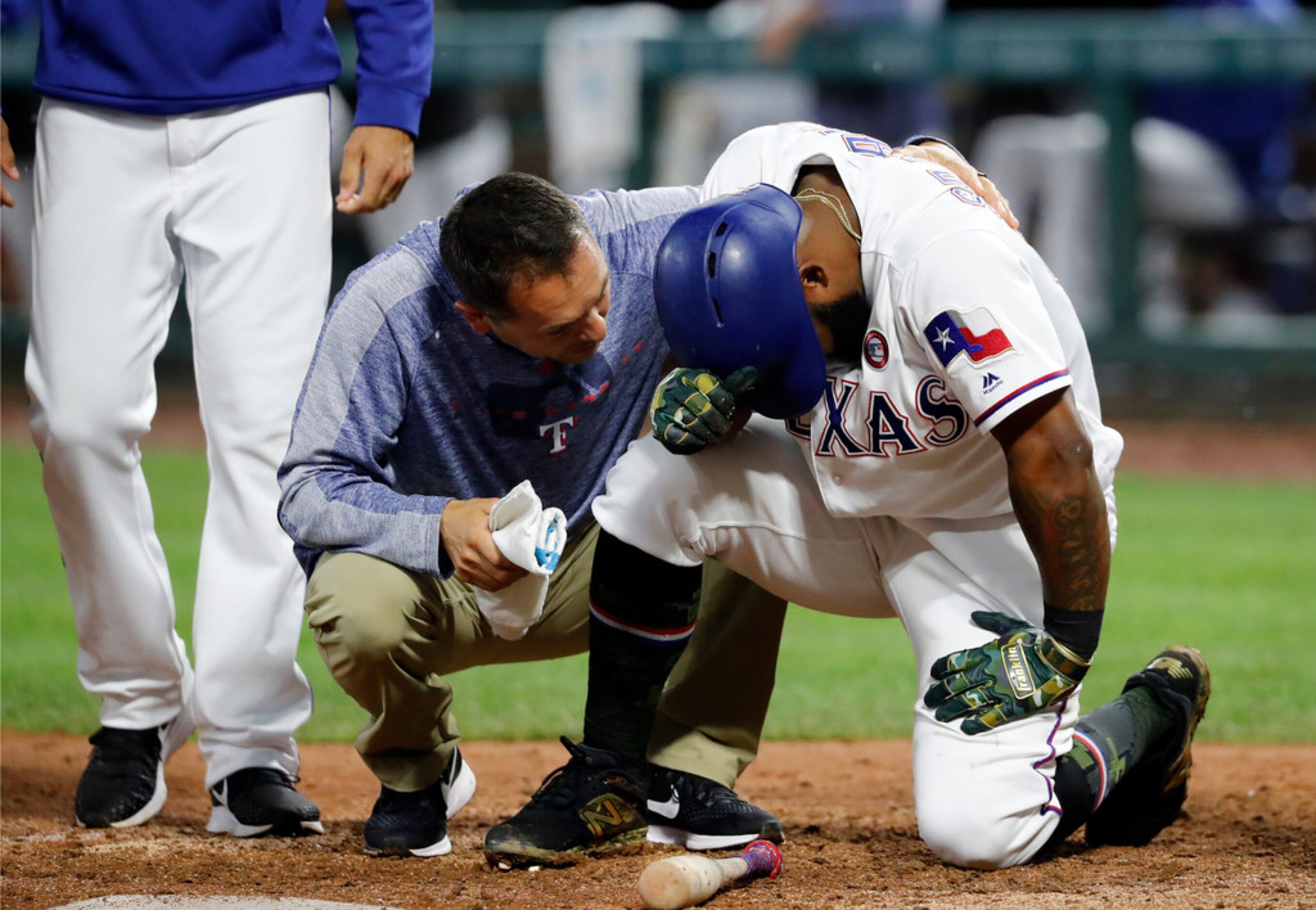 A member of the staff, center, and manager Chris Woodward, left, check on Texas Rangers'...