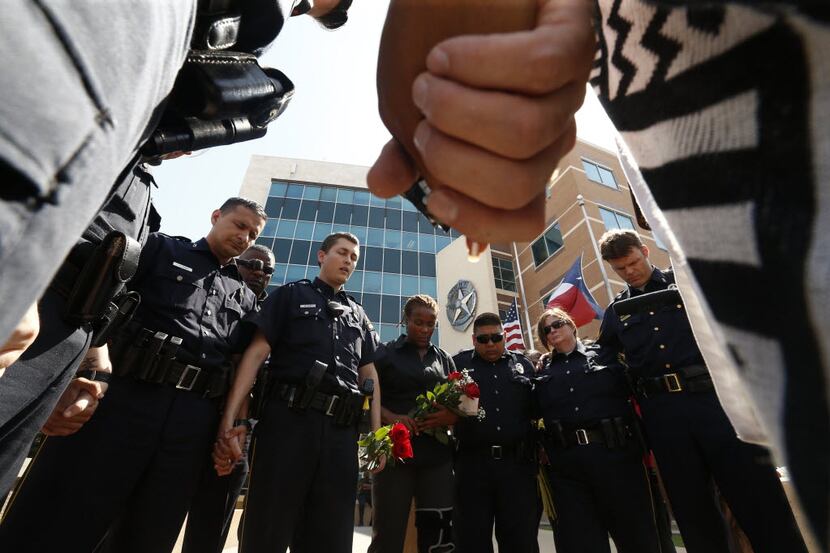 Dallas Police pray in front of Jack Evans Police Headquarters in Dallas on Friday July 8,...
