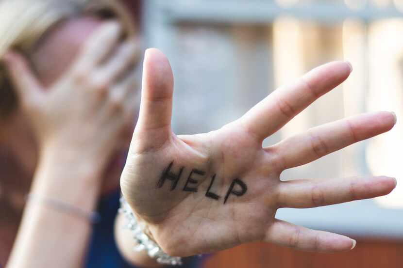 A woman holds out her hand with the word "help" written across it.