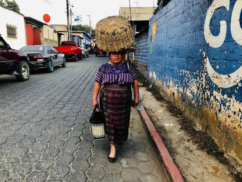 A woman in traditional indigenous dress walks the streets of San Martin Jilotepeque,...