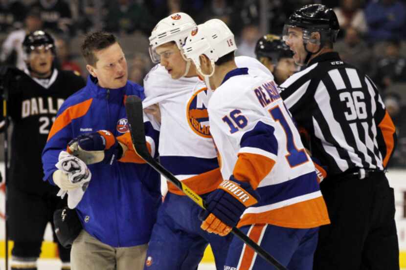 New York right wing Nino Niederreiter (center) is helped from the ice by teammate Marty...
