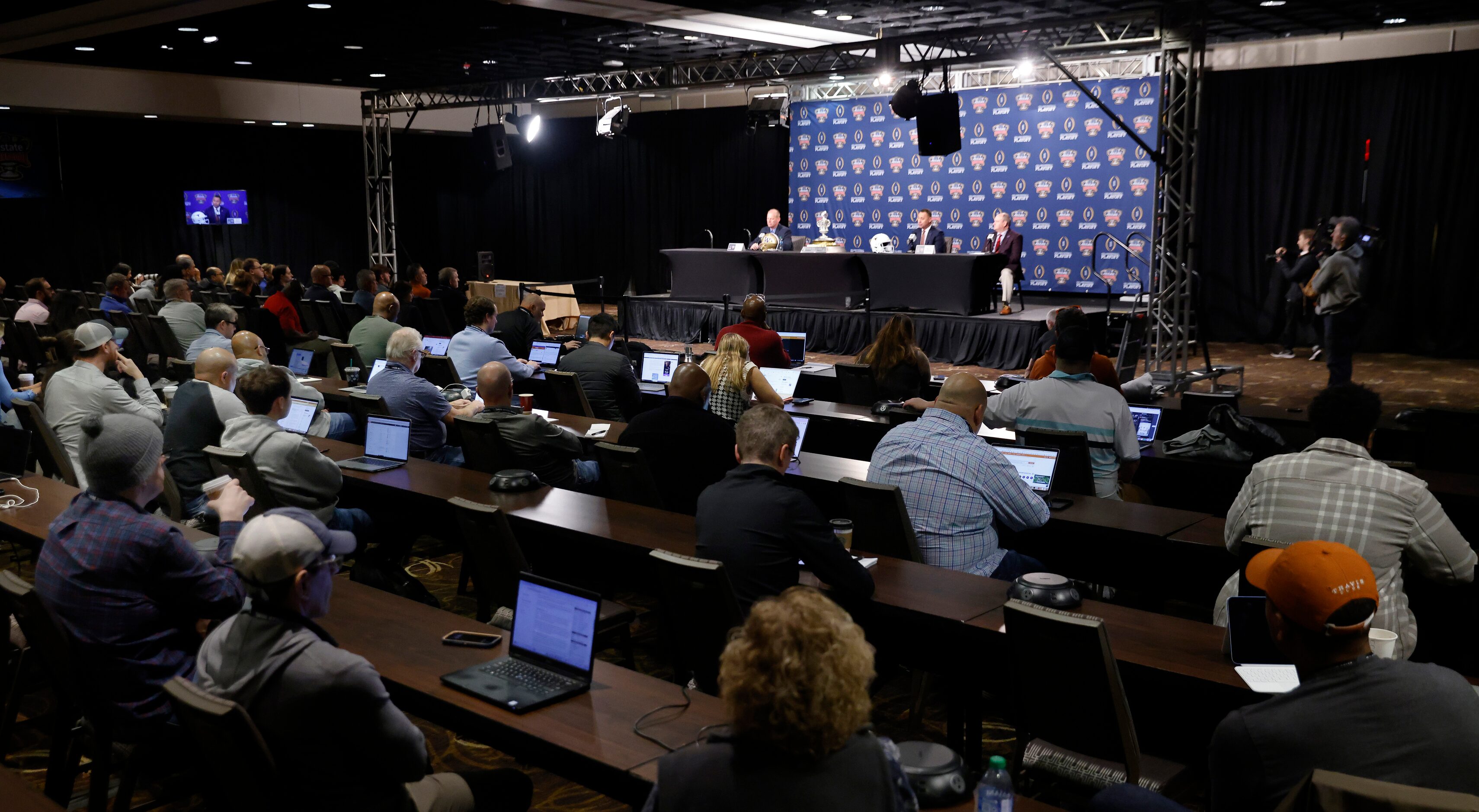 Washington head coach Kalen DeBoer and Texas head coach Steve Sarkisian (on stage) hold a...