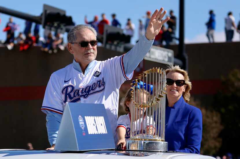 Riding with the Commissioner's Trophy, Texas Rangers manager Bruce Bochy, left, waves to...