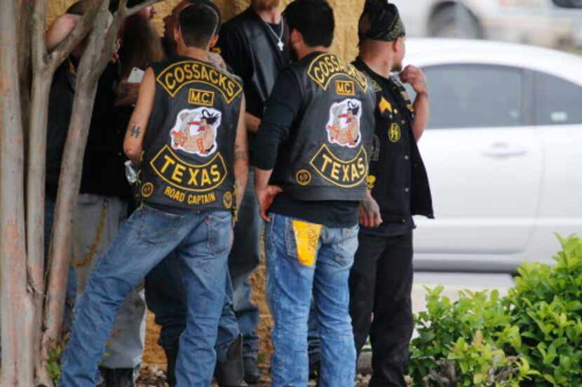 
Bikers congregate against a wall while authorities investigate Sunday's gang shootout at a...
