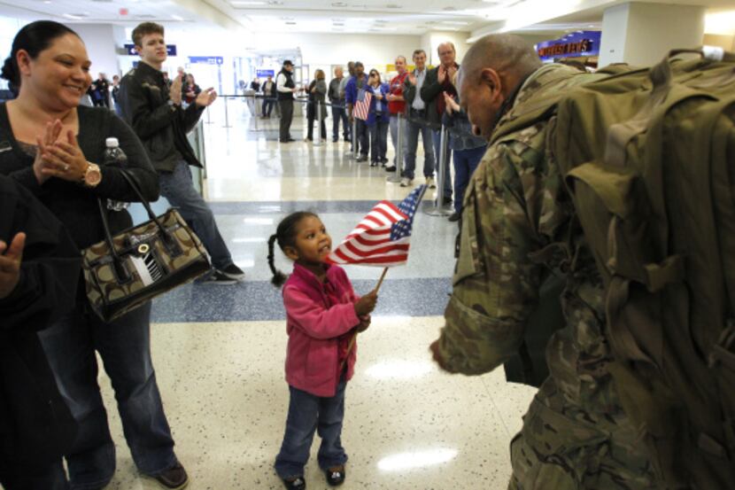Delilah Henry, 3, greets a soldier with a smile and a flag as she waited with her mother...