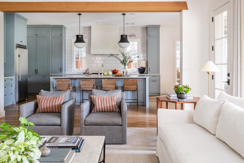 Kitchen with blue-gray cabinets and white range hood, with white sofas and gray chairs in...