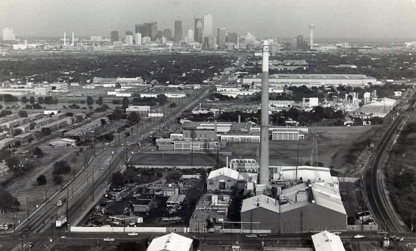 The skyline of Dallas sprawls behind the RSR Corp. smokestack in West Dallas in a photo...
