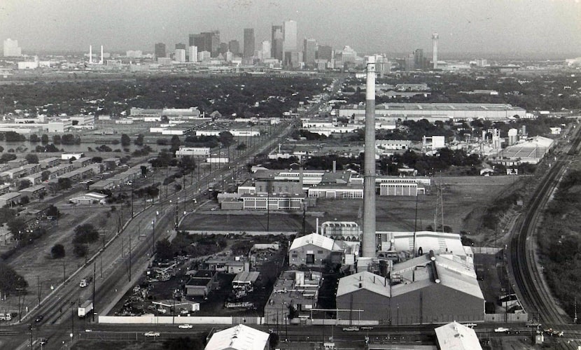 The skyline of Dallas sprawls behind the RSR Corp. smokestack in West Dallas in a photo...