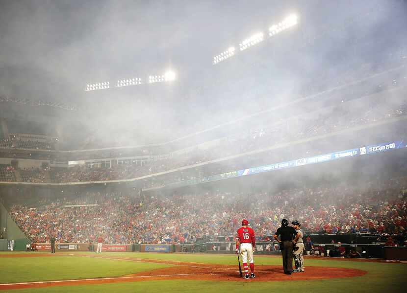 Texas Rangers left fielder Ryan Rua waited to bat as the smoke from the fireworks following...