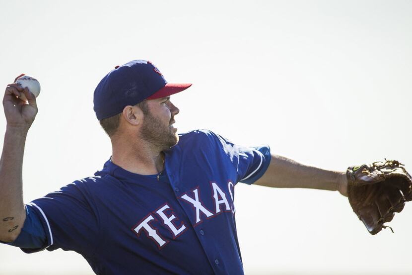 Texas Rangers pitcher Colby Lewis plays catch during a spring training workout at the team's...