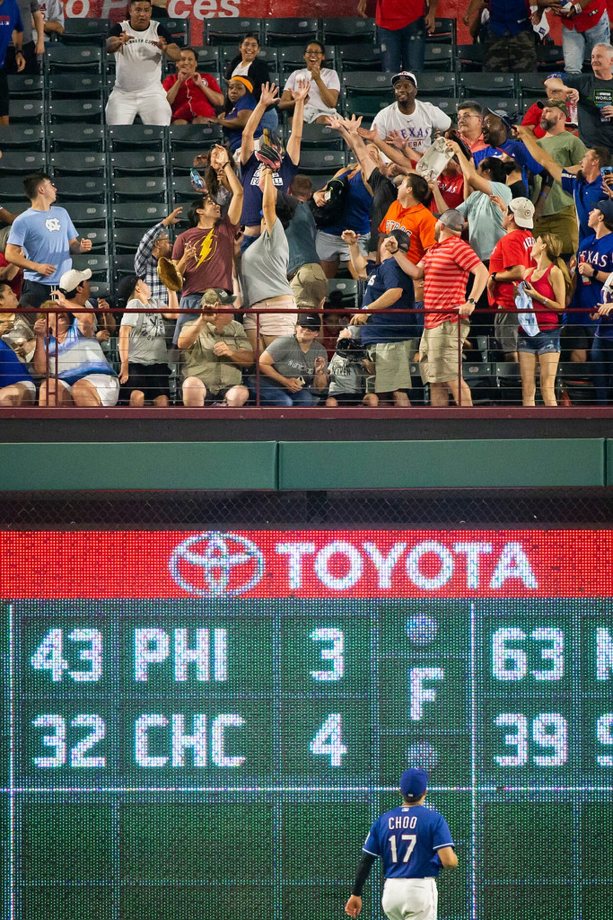 Texas Rangers left fielder Shin-Soo Choo watches fans reach for a home run off the bat of...