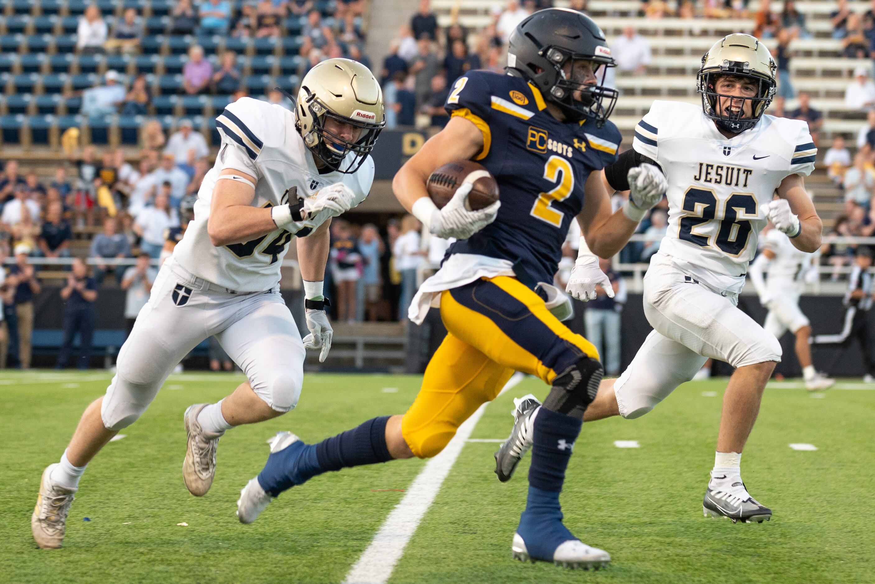 Jesuit defenders junior Grayson Wombacher (54), left, and  junior Bobby Musso (26) chase...