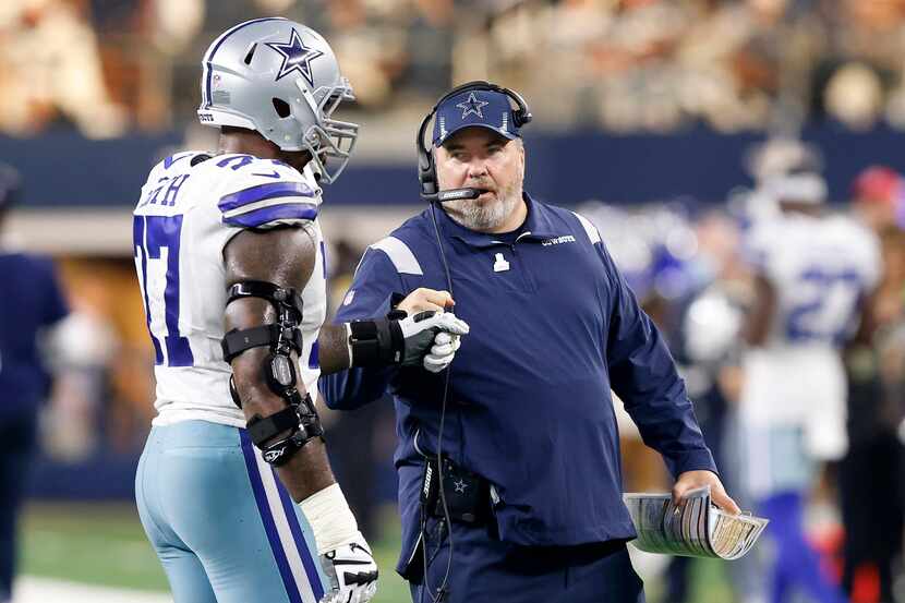 Dallas Cowboys head coach Mike McCarthy gives a fist bump to offensive tackle Tyron Smith...