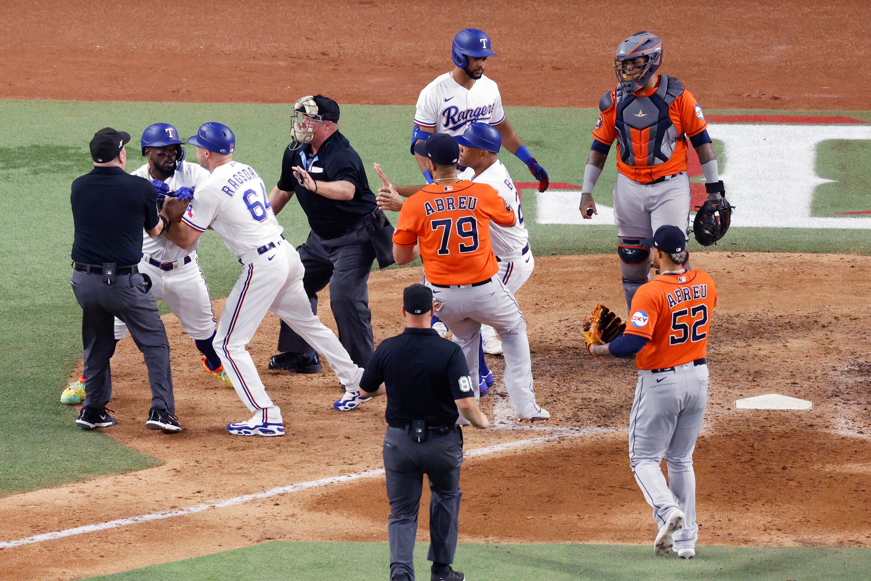 Texas Rangers right fielder Adolis Garcia (53) is restrained by first base coach Corey...