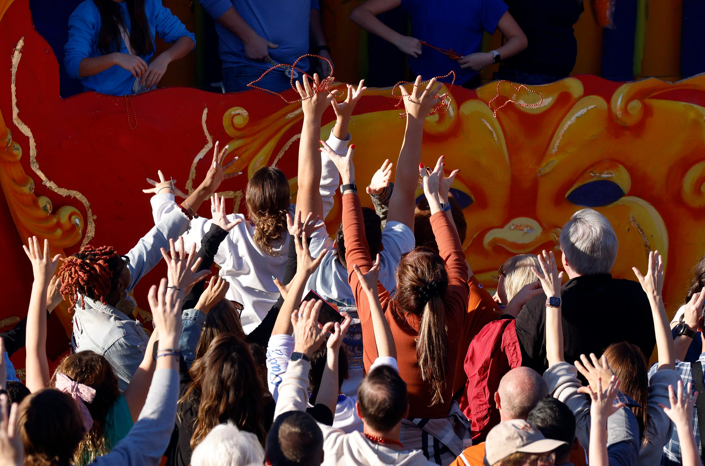 Texas Longhorns fans reach for beads thrown from a float during the Mardi Gras-style...