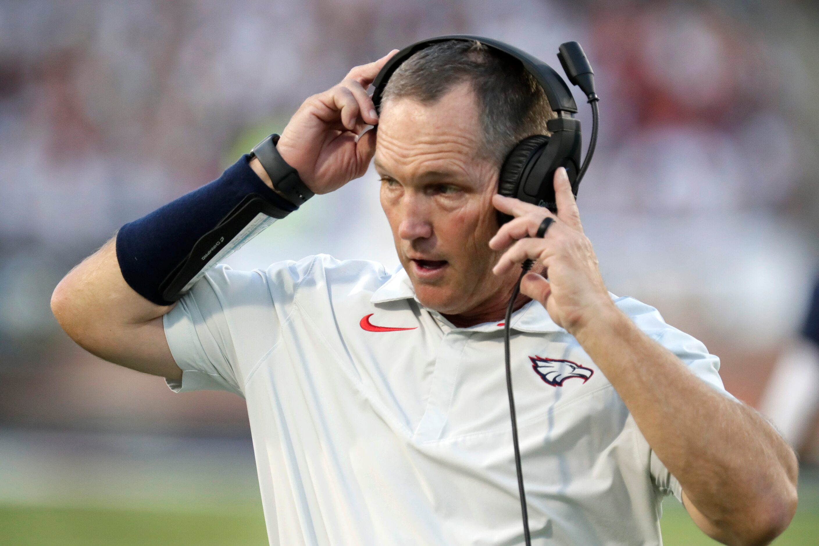 Allen High School head coach Lee Wiginton puts on his head set during the first half as...