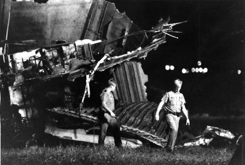 Investigators walk past the debris just before daybreak Saturday morning at the DFW Airport.