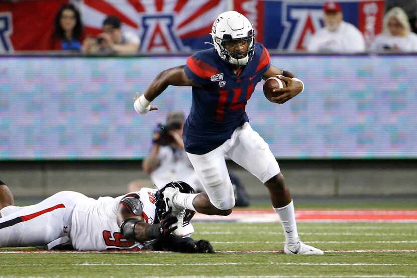 Arizona quarterback Khalil Tate (14) eludes the tackle of Texas Tech defensive lineman...