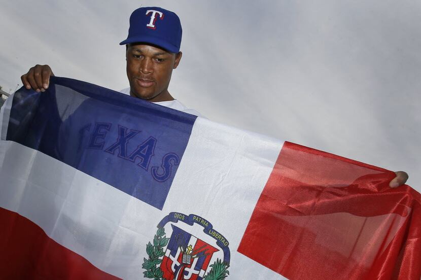 Texas third baseman Adrian Beltre poses with the Dominican Republic flag at photo day during...