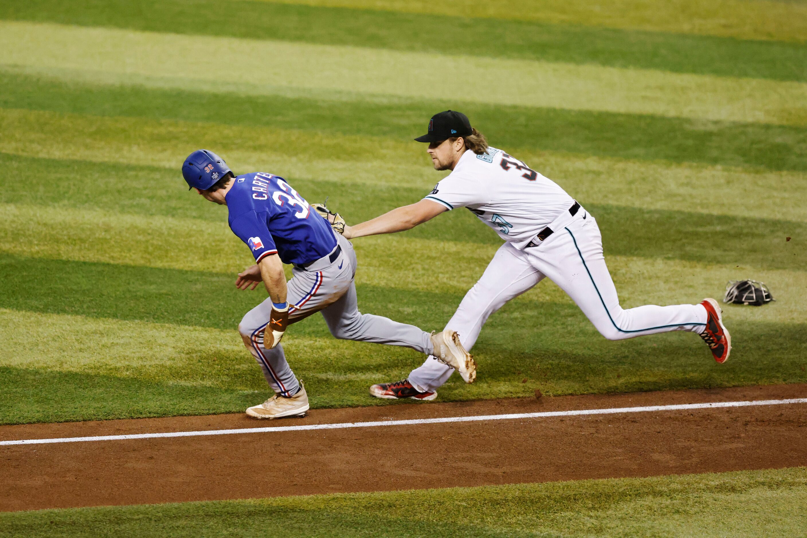 Arizona Diamondbacks relief pitcher Kevin Ginkel, left, tags out Texas Rangers Evan Carter,...