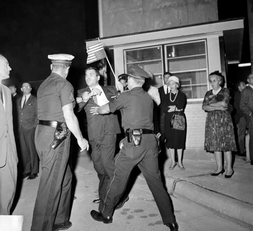 Police grab a flag-waving anti-U.N. demonstrator as he tried to get near Adlai Stevenson as...