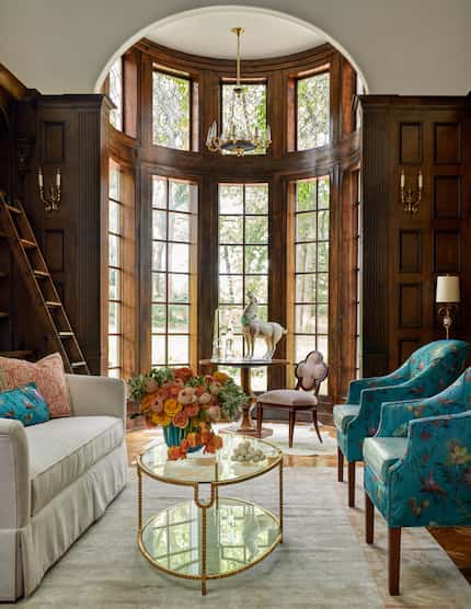 A rounded alcove in a library lets in natural light through many windows, in the foreground...