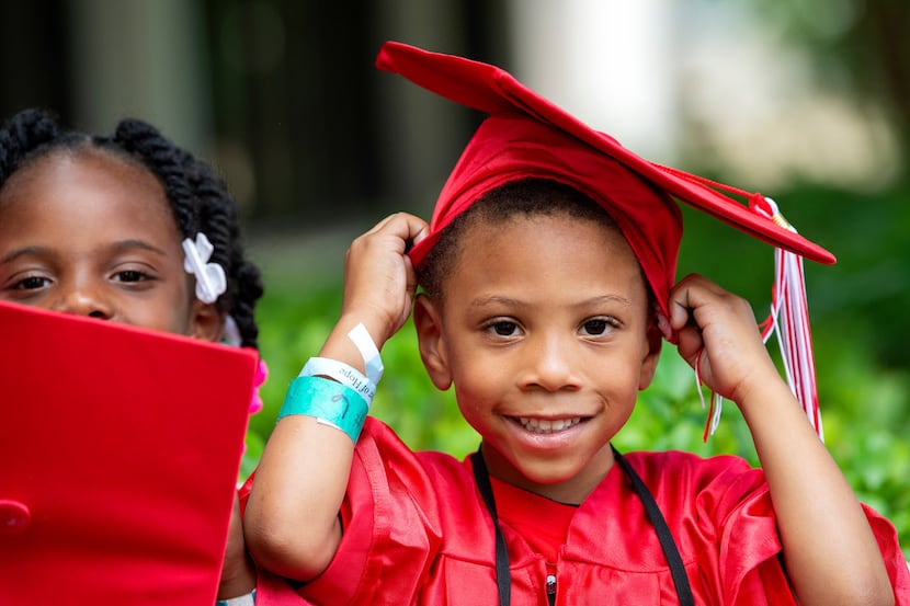 Jerryian, 4, adjust his cap while Zy'Kia, 5, looks on before a graduation ceremony for Kids'...