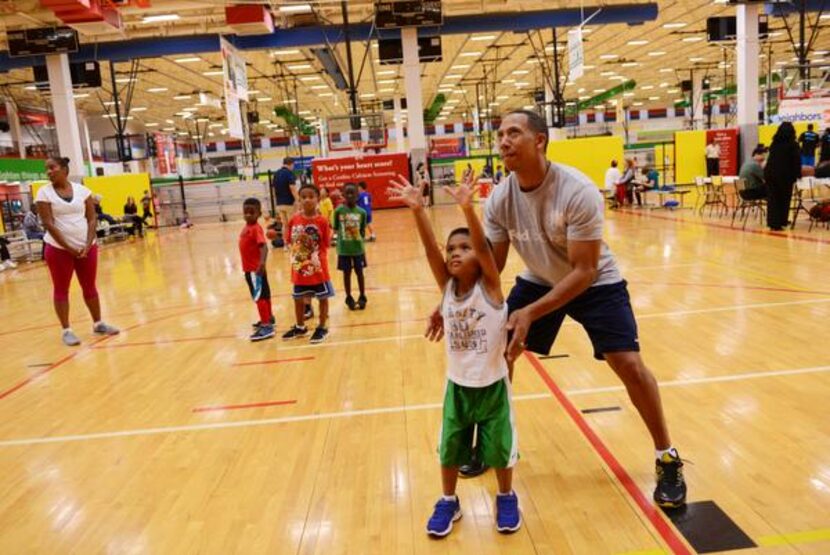 
Volunteer coach Terry Scott helps Ryan Ung, 5, take a practice shot at Plano Sports...