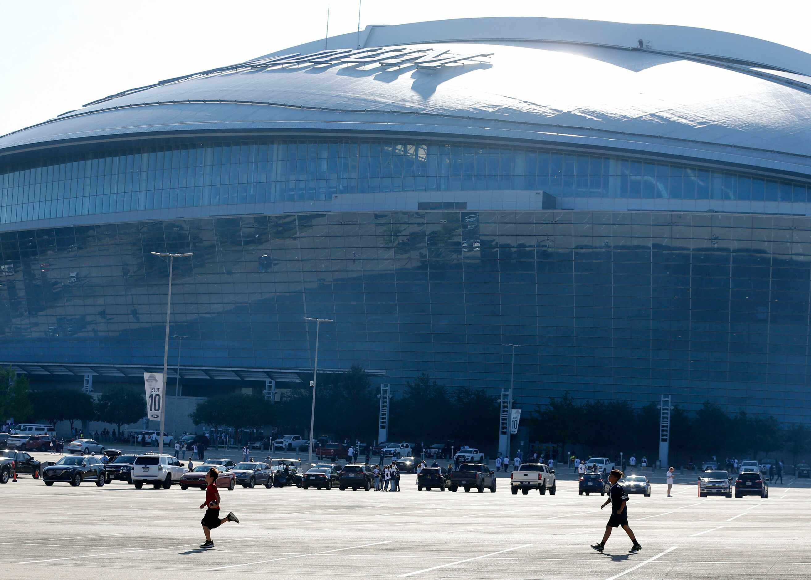 Two kids play football on the AT&T Stadium parking lot before the start of a NFL football...
