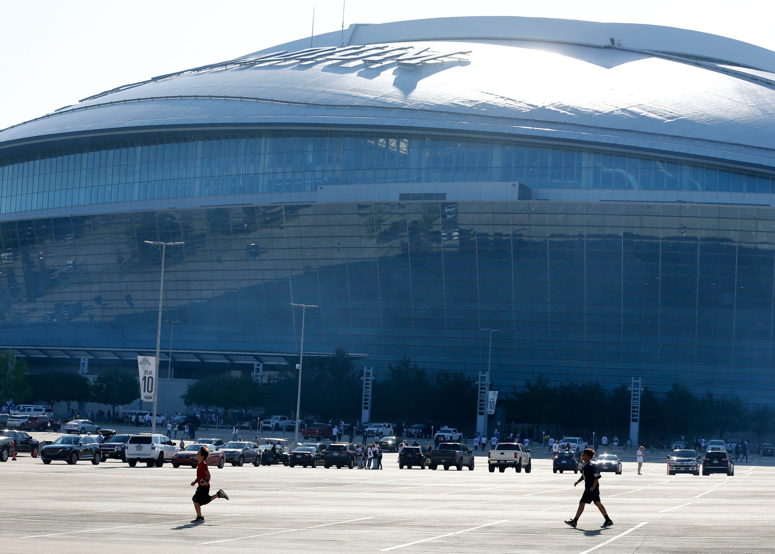 Two kids play football on the AT&T Stadium parking lot before the start of a NFL football...