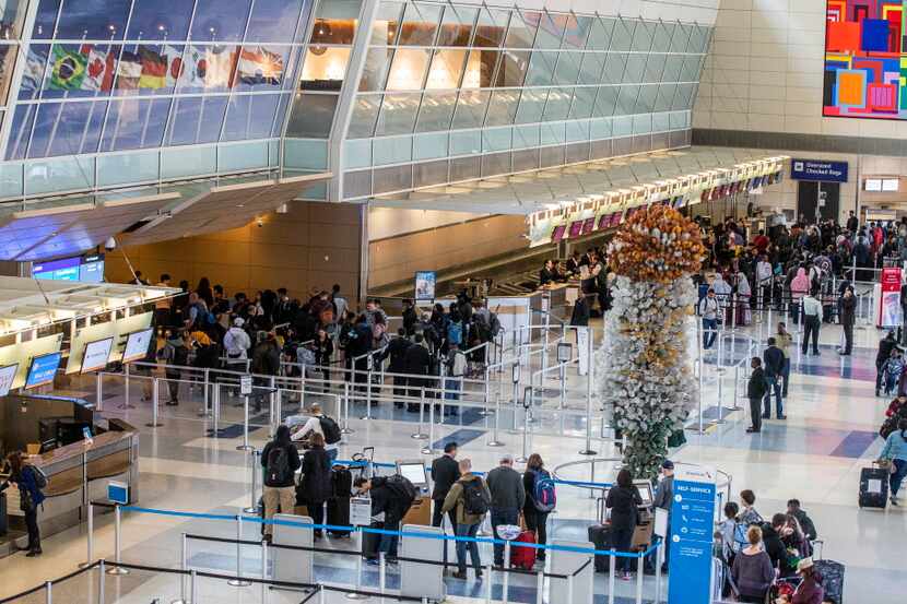 Travelers make their way thought at DFW International Airport security Terminal D on Friday,...