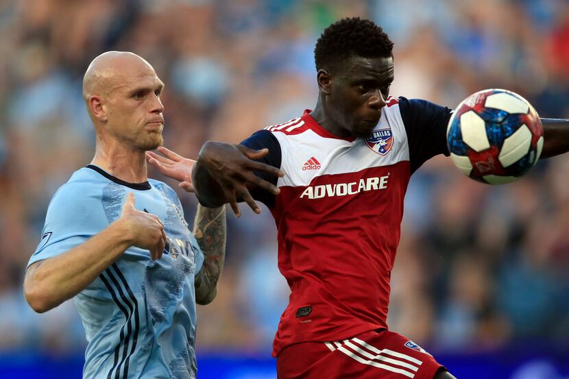 FC Dallas forward Dominique Badji, right, plays the ball in front of Sporting Kansas City...