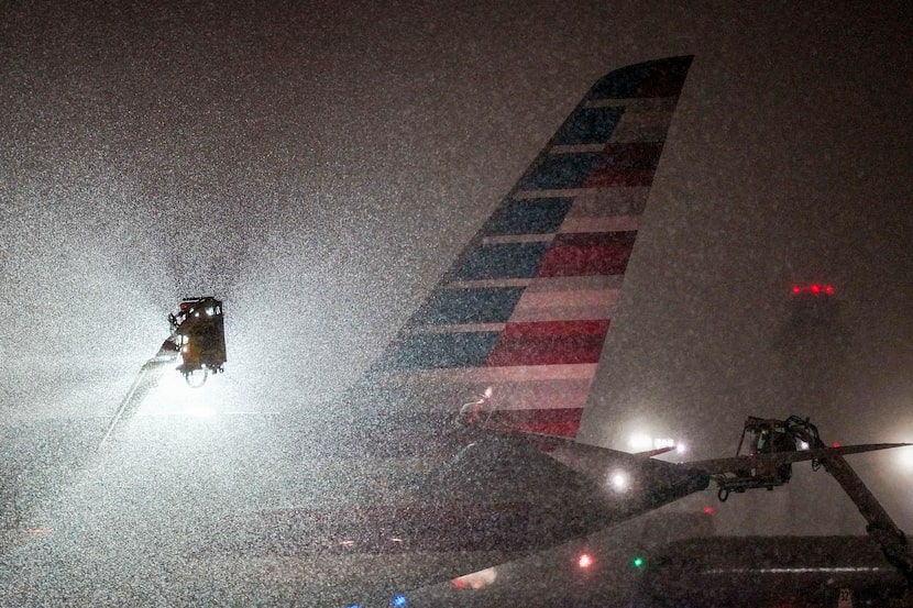 An American Airlines aircraft goes through deicing procedures as snow falls at DFW...