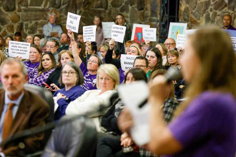 People raise signs to oppose banning books about gender fluidity during a Keller ISD school...