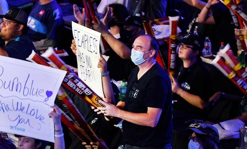 Dallas Fuel fan Collin Corbett (center) slaps his boom sticks as he cheers the team during...