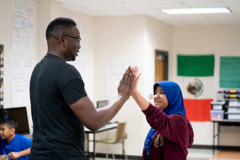 Mentor John Gray gives Sam Tasby Middle School student Nee Sar Sam a high-five during the...
