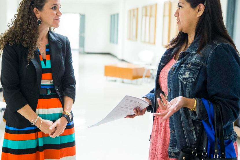 
Principal Sarah Ritsema, left, helps Calette Benavidez with paperwork for her daughters...