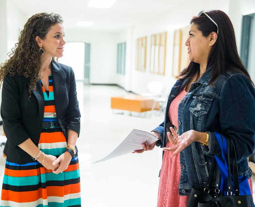 
Principal Sarah Ritsema, left, helps Calette Benavidez with paperwork for her daughters...