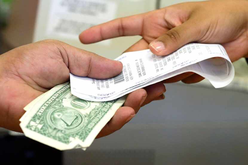 FILE - In this Friday, Nov. 23, 2012 file photo, a cashier hands a customer his change and...