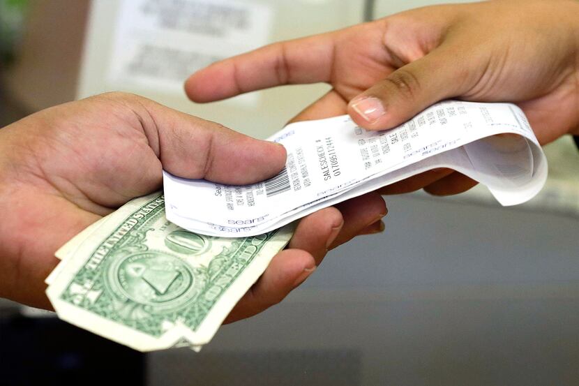 FILE - In this Friday, Nov. 23, 2012 file photo, a cashier hands a customer his change and...